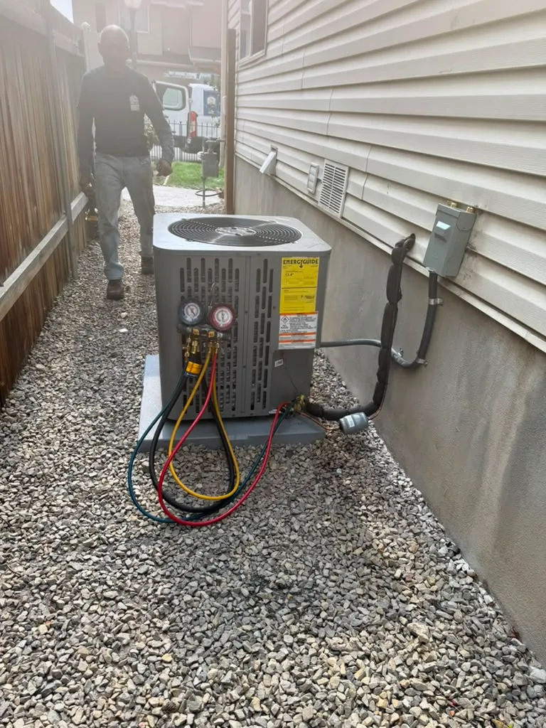 Lucas Heating and Air technician commissioning a new RunTru air conditioner with gauges connected in a West Jordan side yard