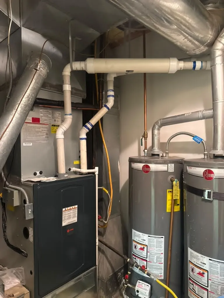 High-efficiency furnace installed by Lucas Heating and Air with PVC venting beside a gas water heater