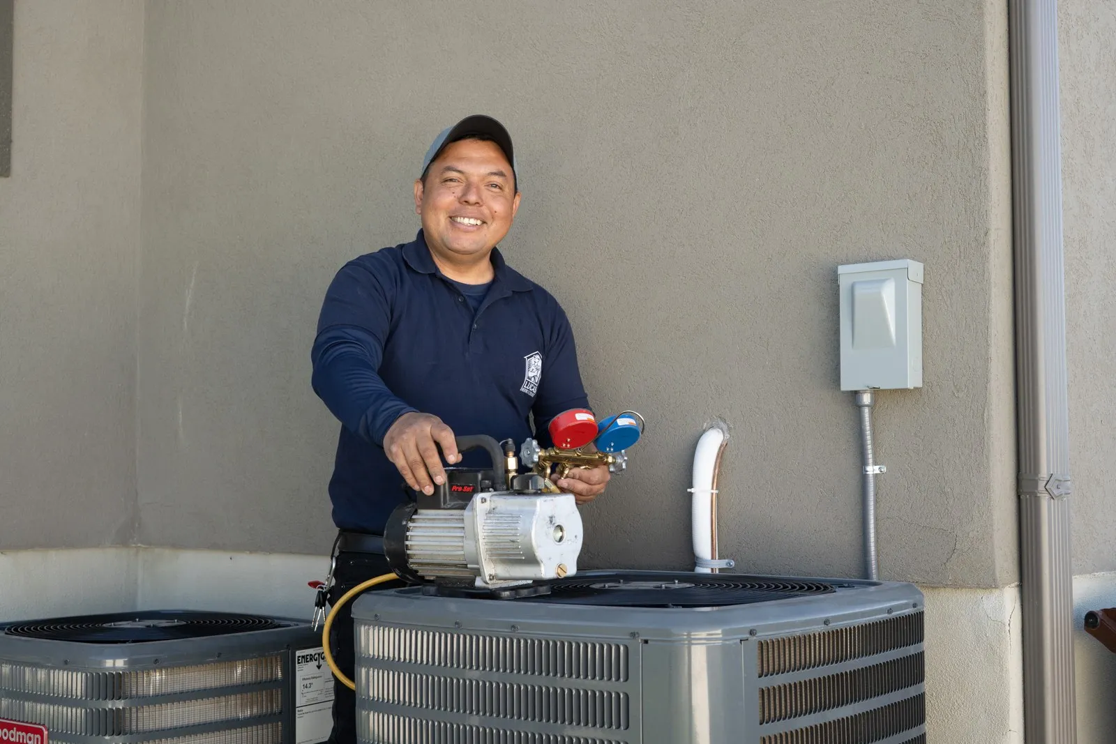 Lucas Heating and Air technician with a vacuum pump commissioning two new condensers