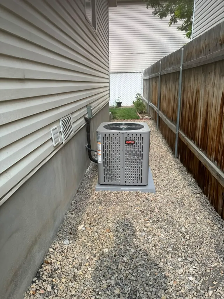 Finished RunTru air conditioner installed on a gravel bed in a narrow West Jordan side yard