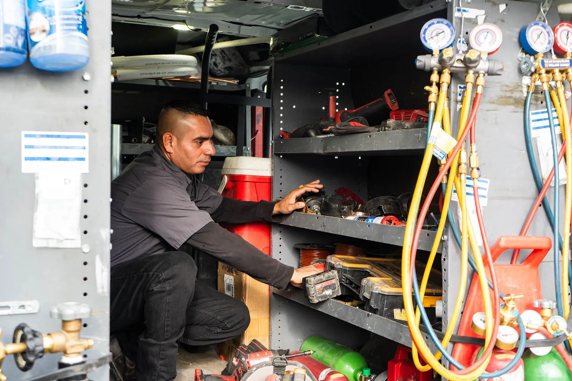 Lucas Heating and Air technician selecting gauges and tools inside a service van